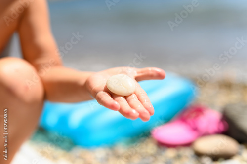 round white sea stone in a child s hand on the background of the beach