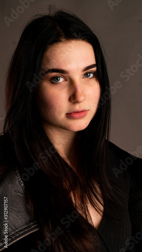 High Fashion girl model look in black suit. Studio shot of slim sexy brunette wears bra and black jacket. Stylish portrait of woman with bob hairstyle and makeup isolated on grey background.