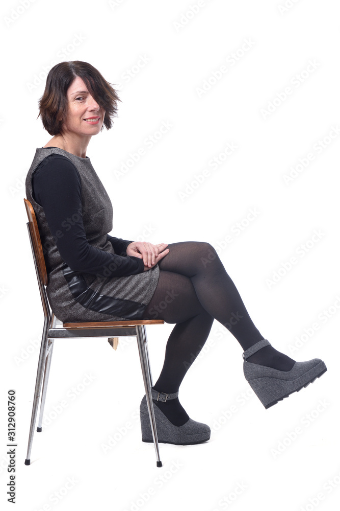 woman in dress sitting on a white background lengs crossed, looking at camera woman in dress sitting on a white background lengs crossed, looking at camera