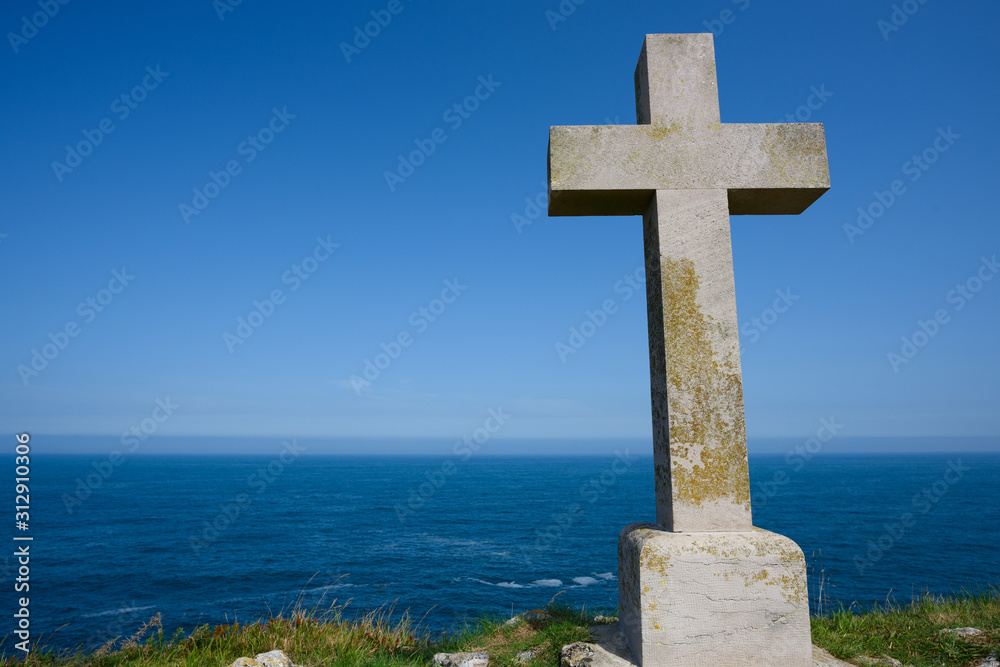 Cross on rock at ocean coast at clear day