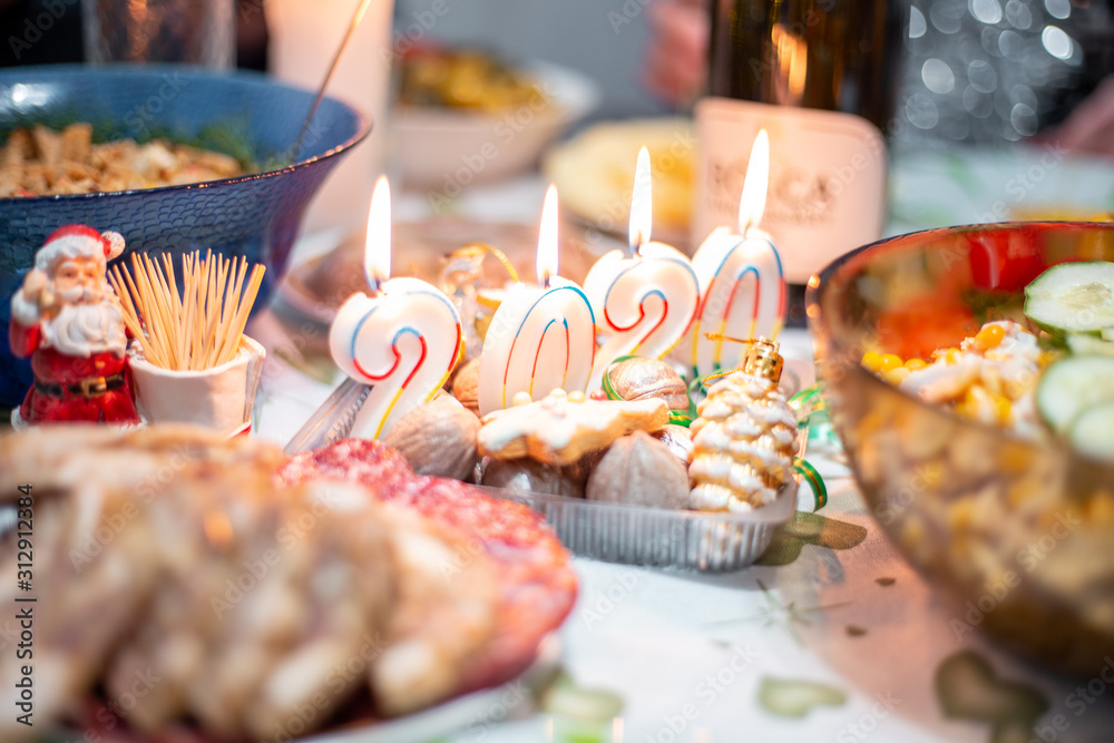 Christmas table with a festive dinner and candles from the numbers 2020 Christmas table with a festive dinner and candles from the numbers 2020