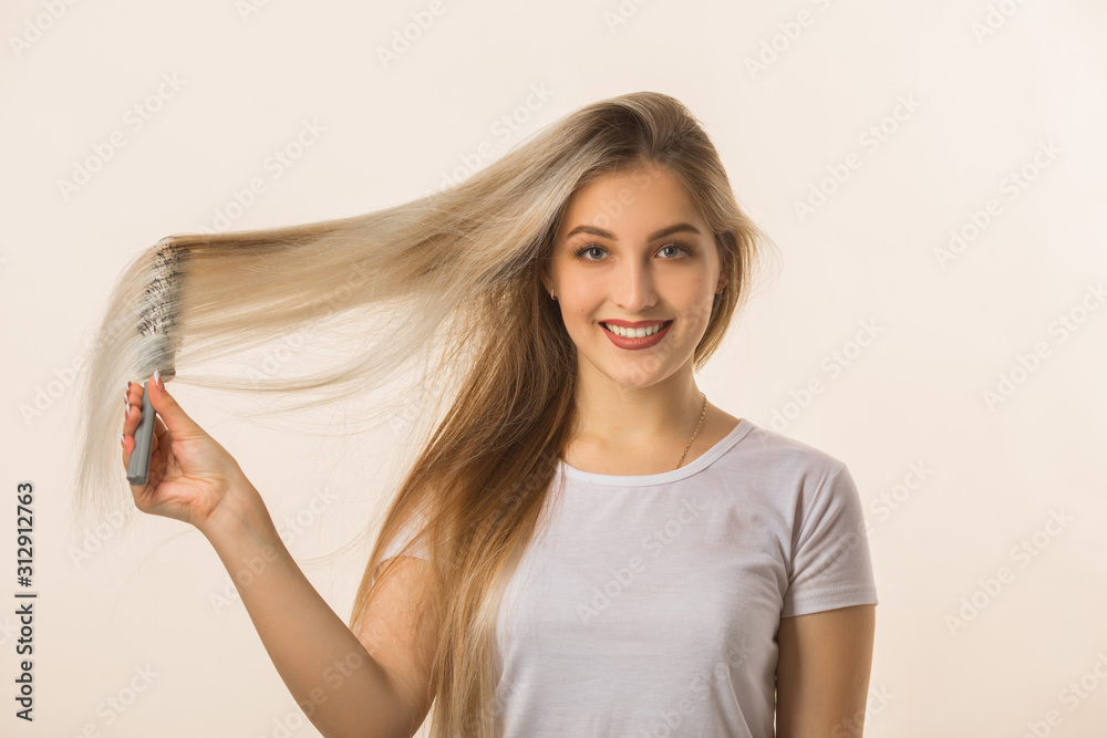 beautiful young woman on a beige background with her hair with a comb beautiful young woman on a beige background with her hair with a comb