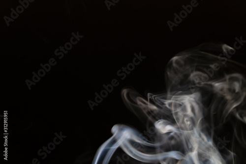 Abstract smoke background with copy space on black background. Blue-white smoke rising from the incense stick