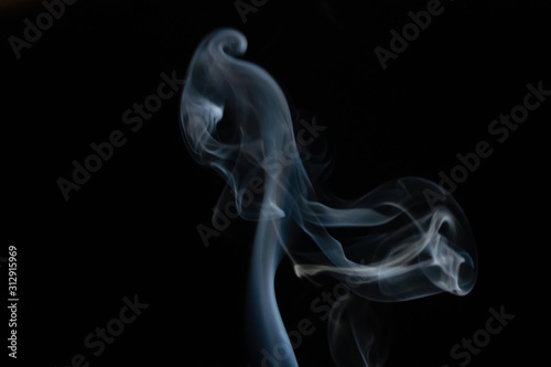 Abstract smoke background with copy space on black background. Blue-white smoke rising from the incense stick