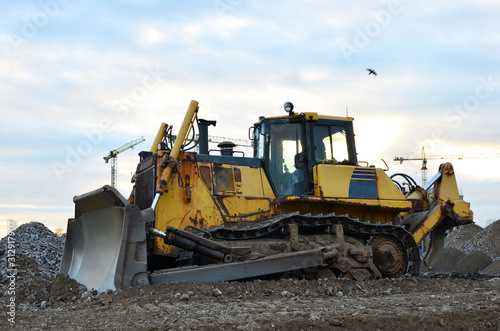 Track-type bulldozer on construction site. Land clearing, grading, pool excavation, utility trenching and foundation digging during of large construction jobs. Earth-moving equipment