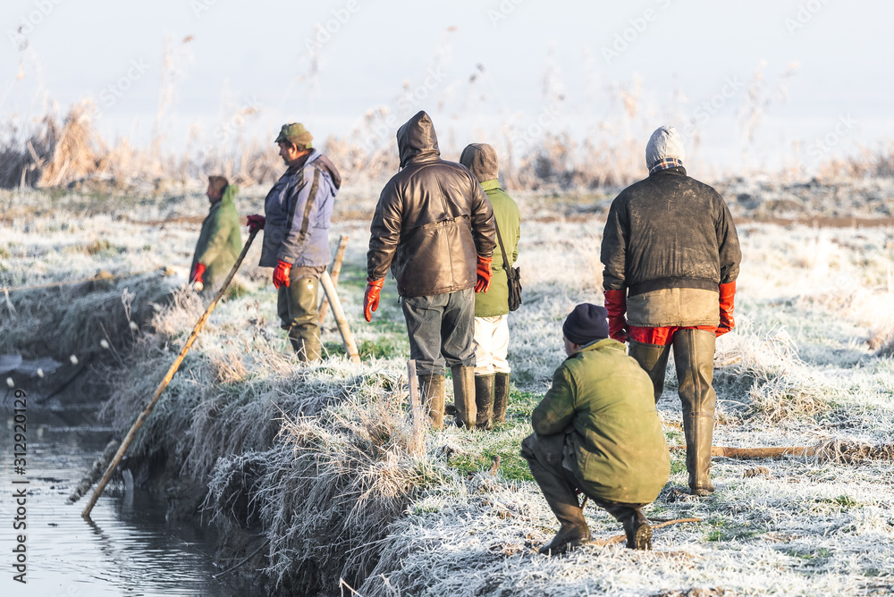 Naklejka premium Several fishermen pull in his nets full of fish during the winter period