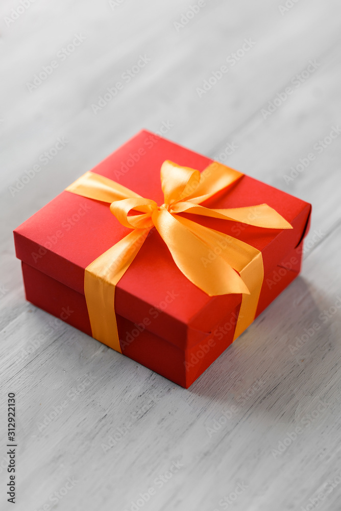 Obraz premium red box tied with a gold ribbon. the ribbon is tied on a box in the form of a beautiful bow. holiday gift concept
