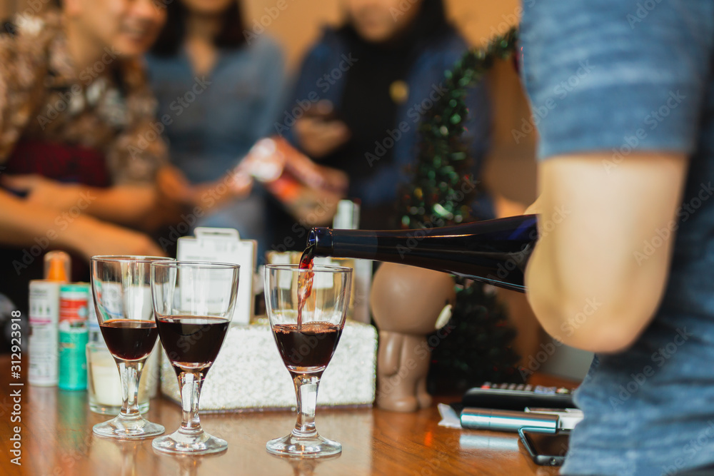 Hand pouring red wine in glass during party with friends. Hand pouring red wine in glass during party with friends.