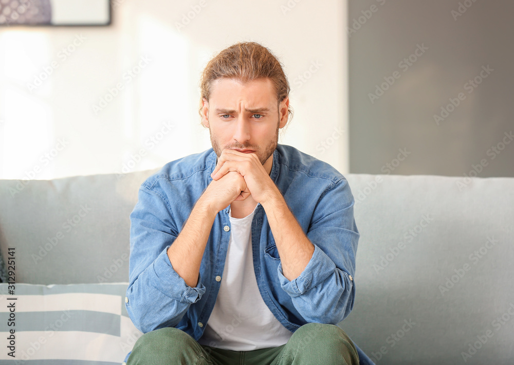 Depressed man sitting on sofa at home Depressed man sitting on sofa at home
