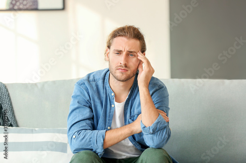 Depressed man sitting on sofa at home