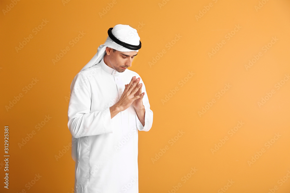 Handsome Arab man praying on color background