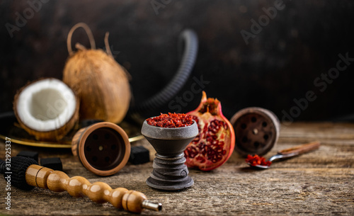 Stone hookah head on old rustic table with fruit flavoured tobacco photo