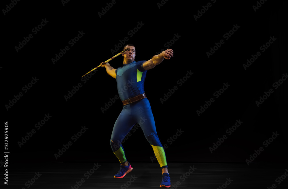 Male athlete practices in throwing javelin on black background in neon light. Professional sportsman training in action, motion. Concept of healthy lifestyle, movement, activity, competition