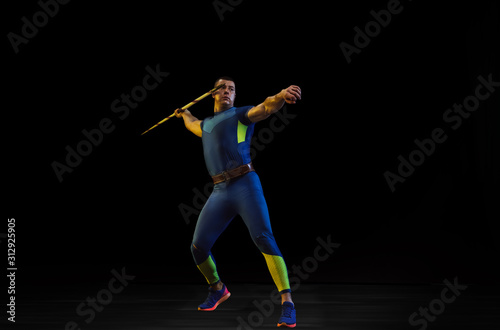 Male athlete practices in throwing javelin on black background in neon light. Professional sportsman training in action, motion. Concept of healthy lifestyle, movement, activity, competition © master1305