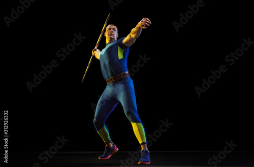 Male athlete practices in throwing javelin on black background in neon light. Professional sportsman training in action  motion. Concept of healthy lifestyle  movement  activity  competition