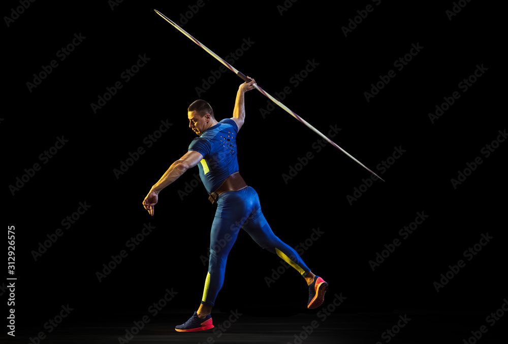 Male athlete practices in throwing javelin on black background in neon light. Professional sportsman training in action, motion. Concept of healthy lifestyle, movement, activity, competition Male athlete practices in throwing javelin on black background in neon light. Professional sportsman training in action, motion. Concept of healthy lifestyle, movement, activity, competition