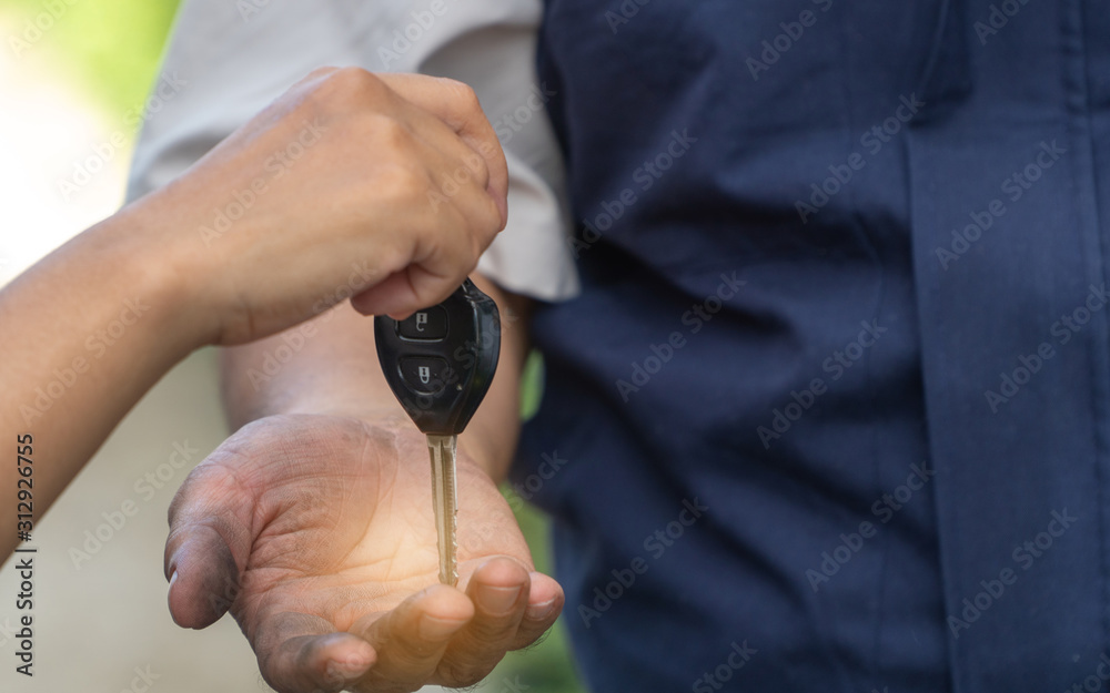 Fototapeta premium Close up of the woman hand is sending the car keys to the car mechanic. The concept of trust And confidence in using the service