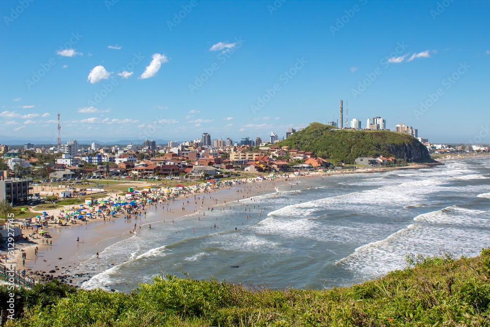 Falésia, e vegetação típica ao fundo a praia da Cal, da cidade de Torres em dia de sol, praia tropical, Brasil