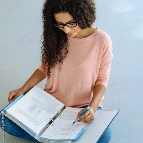 Young African student sitting working on her notes photo