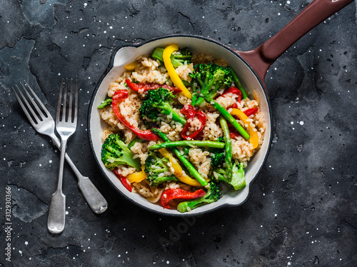 Vegetarian vegetable paella in a cooking pan on a dark background, top view