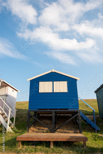 Colourful wooden beach huts facing the ocean at Whitstable coast, Kent district England.
