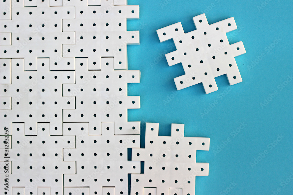 Naklejka premium White puzzle pieces on the turquoise background show cohesion, teamwork and agreement.