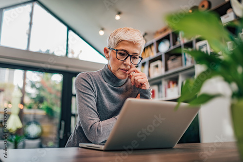 Portrait of a serious senior woman looking at laptop.