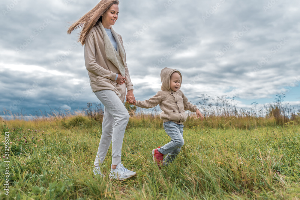 happy family, woman s mother and small child, boy s son, walk in field autumn, casual warm clothes, sweater with hood, emotions of joy of fun and relaxation, walk on weekend. happy family, woman s mother and small child, boy s son, walk in field autumn, casual warm clothes, sweater with hood, emotions of joy of fun and relaxation, walk on weekend.
