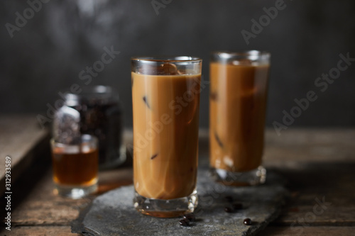 Ice coffee in a tall glass on wooden table..