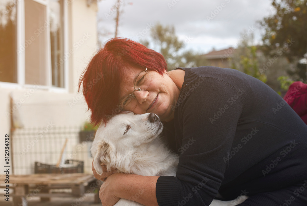 Fototapeta premium Mature woman embracing pet dog in nature