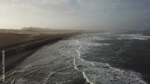 4K aerial drone video view of Namibian Atlantic coastline, Zeila L-758 Walvis Bay stranded rusty shipwreck at sand beach in Skeleton Coast Park landscape with ocean background at Namibia's west coast photo