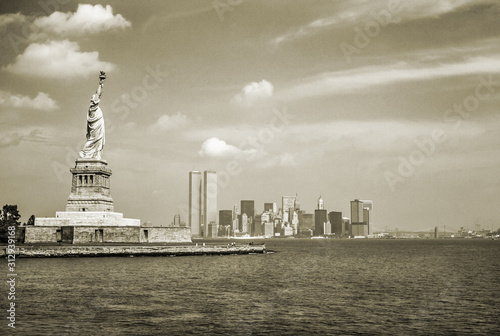 Statue of Liberty and Twin Towers, destroyed in September 11, 2001, of World Trade Center. New York City skyline view from the ferry. Sepia background, vintage style.