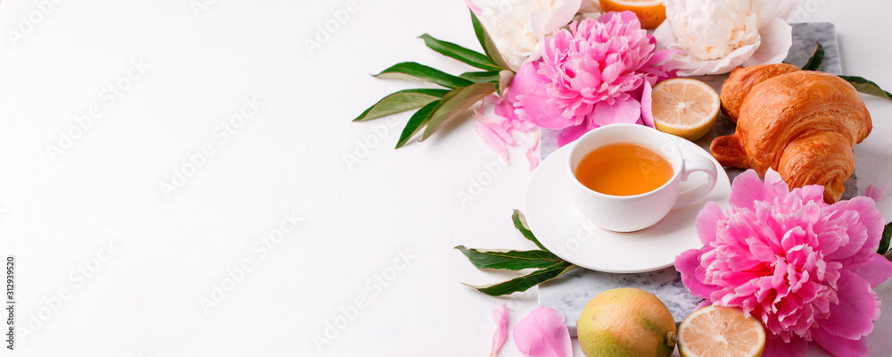 Peonies and cup of tea on white background. Spring flowers. Spring breakfast background. Greeting card for Valentine's Woman's Mother's Day, wedding, banner Peonies and cup of tea on white background. Spring flowers. Spring breakfast background. Greeting card for Valentine's Woman's Mother's Day, wedding, banner