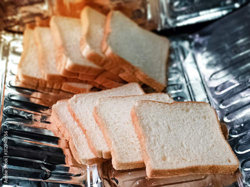 In selective focus of slice bread,stacked together,put on aluminium tray,prepare for serving,blurry light around