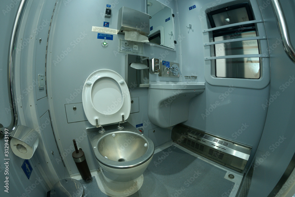 Toilet in a railways sleeping carriage of a passenger train – toilet-bowl, washbasin, mirrors and toilet paper box Toilet in a railways sleeping carriage of a passenger train – toilet-bowl, washbasin, mirrors and toilet paper box