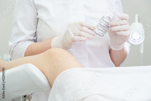 Gynecologist holding vaginal suppositories consulting patient in medical chair