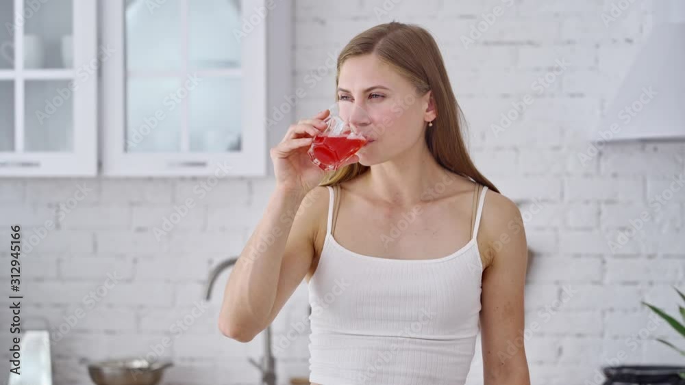 Beautiful woman is drinking fresh at home. Healthy girl holding glass with tasty juice and drinking happily in the morning. Dieting concept. Beautiful woman is drinking fresh at home. Healthy girl holding glass with tasty juice and drinking happily in the morning. Dieting concept.