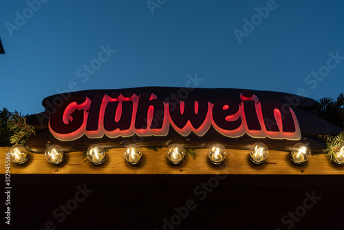 Beleuchteter Glühwein Schriftzug von vorne an Holzverkaufsstand