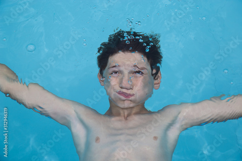 A boy dives backwards underwater in a swimming pool © David.Sch