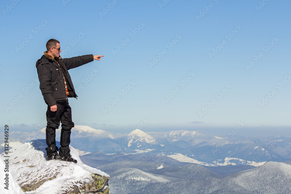 Silhouette of alone tourist standing on snowy mountain top enjoying view and achievement on bright sunny winter day. Adventure, outdoors activities and healthy lifestyle concept.