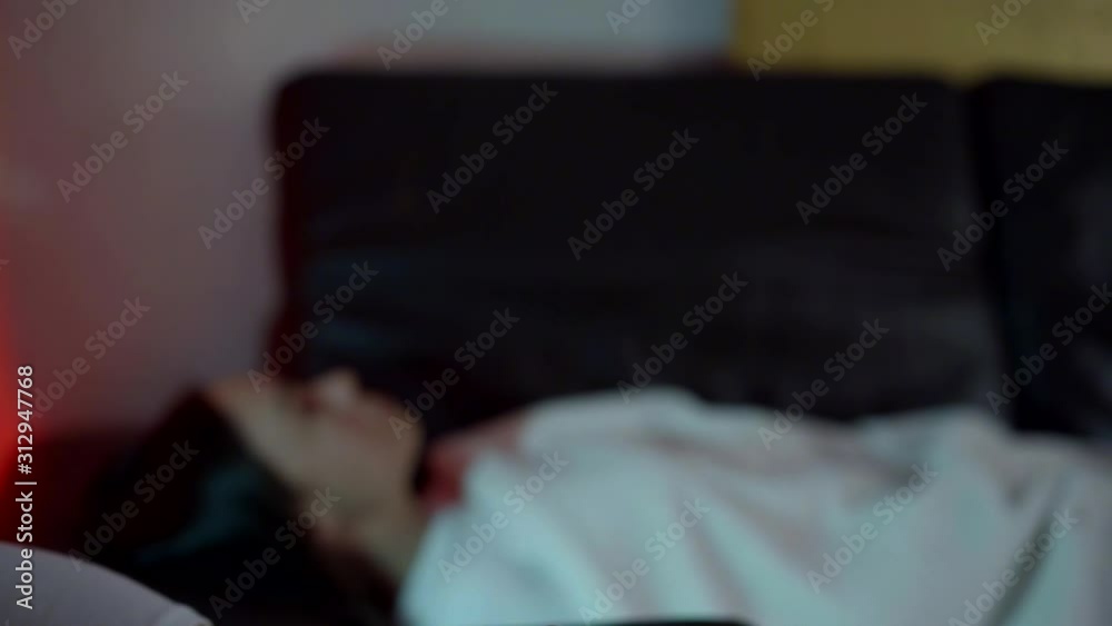 a woman's hand with red nails snaps her fingers. in the background, a girl is seen out of focus. she sleeps on the couch and wakes up with a click