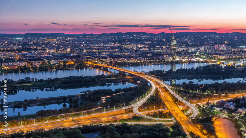 Aerial panoramic view over Vienna city with skyscrapers, historic buildings and a riverside promenade day to night timelapse in Austria.