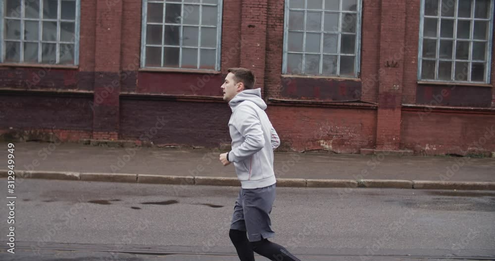 Runner man running on the road in the city. Handsome male athlete training cardio jogging on street with red houses. Runner man running on the road in the city. Handsome male athlete training cardio jogging on street with red houses.