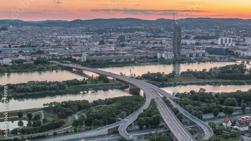 Aerial panoramic view over Vienna city with skyscrapers, historic buildings and a riverside promenade day to night timelapse in Austria.