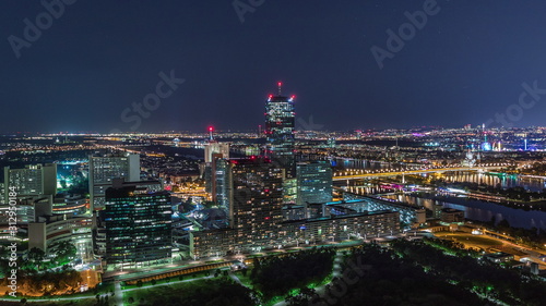 Aerial panoramic view over Vienna city with skyscrapers, historic buildings and a riverside promenade night timelapse in Austria. © neiezhmakov