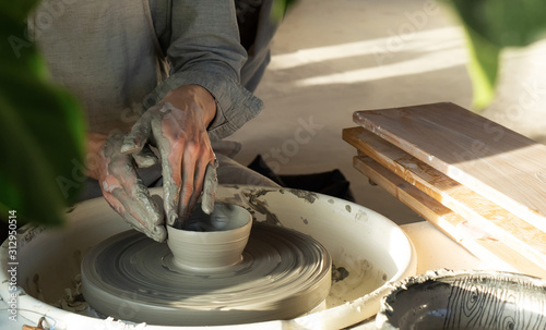 man potter making clay plate in pottery workshop photo