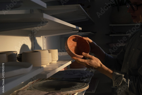 man holding ceramic plate after bisque firing photo