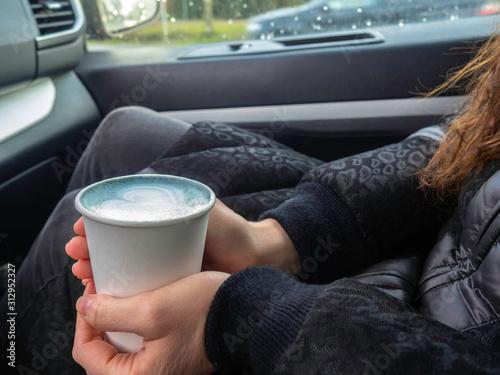Blue matcha latte art in eco friendly paper cup. Main color 2020 year concept. A cup of coffee female hands in car. Minimal composition.