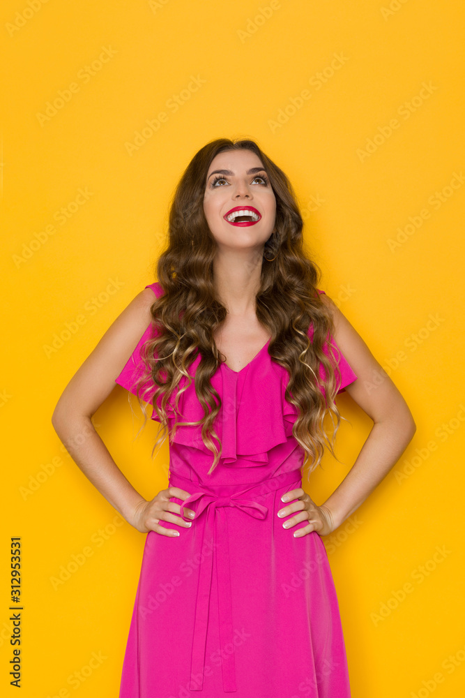 Beautiful Woman In Pink Dress Is Holding Hands On Hip, Looking Up And Smiling