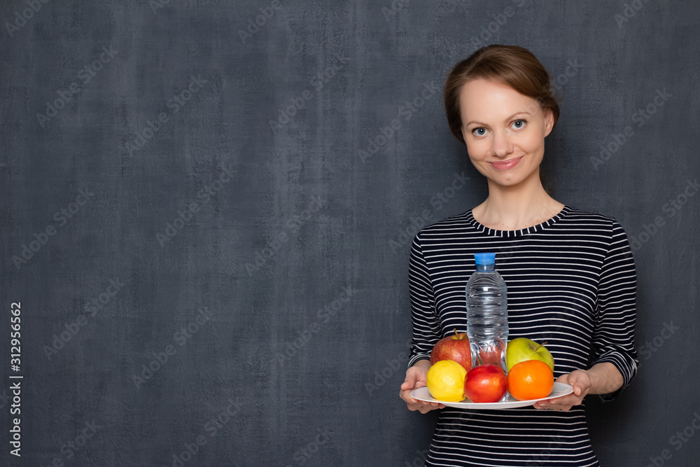 Portrait of happy woman holding plate of fruits and bottle of water Portrait of happy woman holding plate of fruits and bottle of water